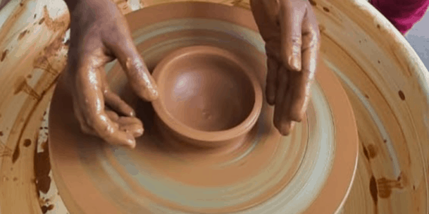 Two hands making pottery using clay in the wheel during pottery making workshop is depicted in this poster 
