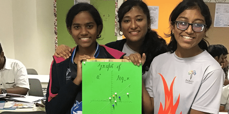 Three girls with smiling holding green craft paper depicting graphs using art items indicating their interest for the maths subject