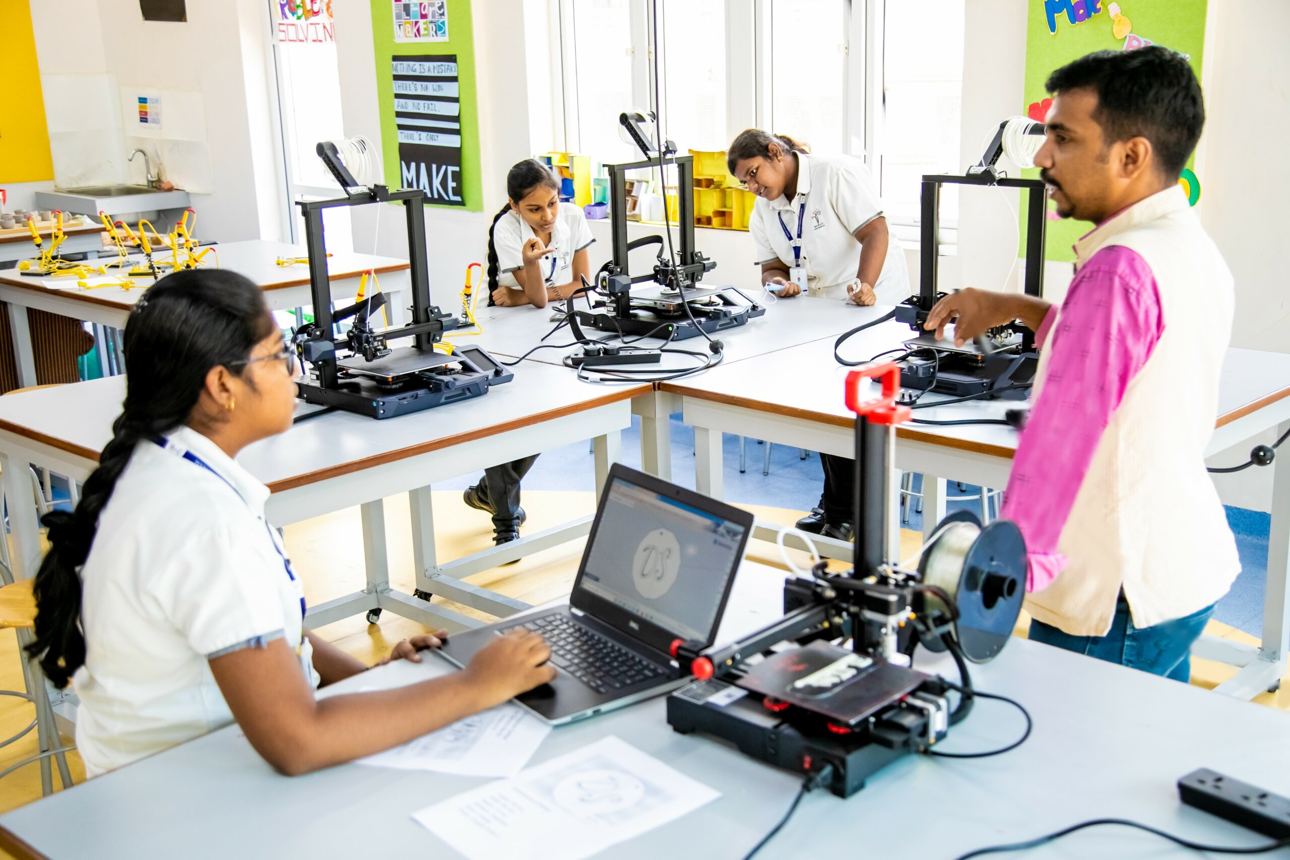 Three students are learning to work with 3D printing machine under the guidance of a senior teacher in a private school in Chennai.