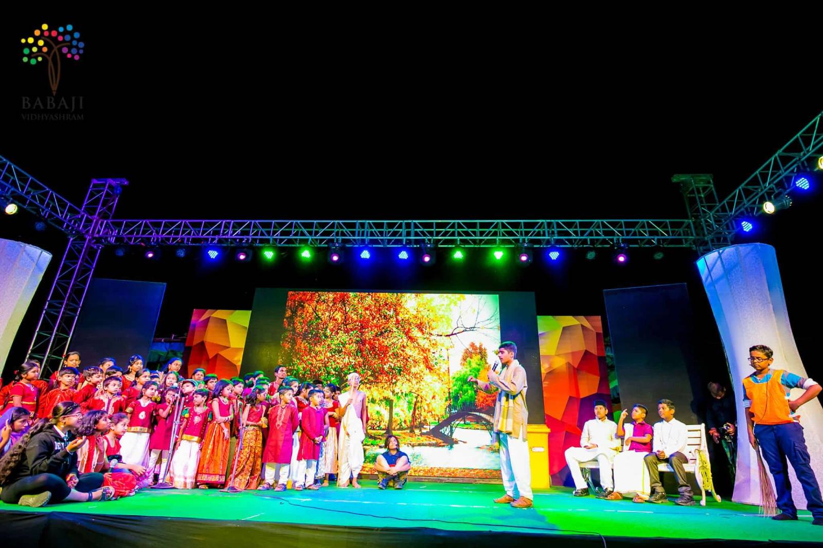 The image shows an active class with students and a teacher along with nature.